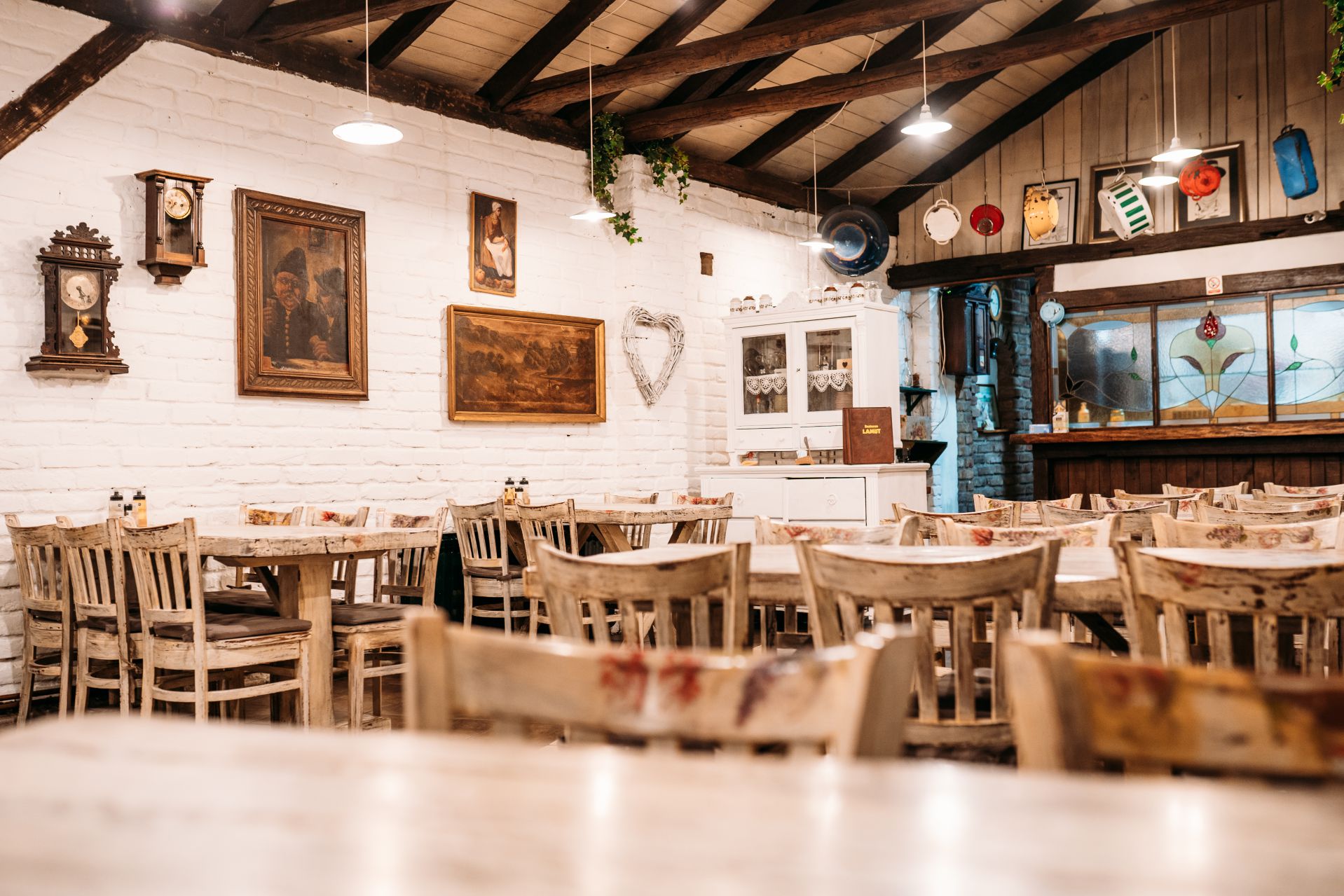 Unutrašnjost restorana Lamut, bijela cigla, drveni stropni grede i stare slike na zidu